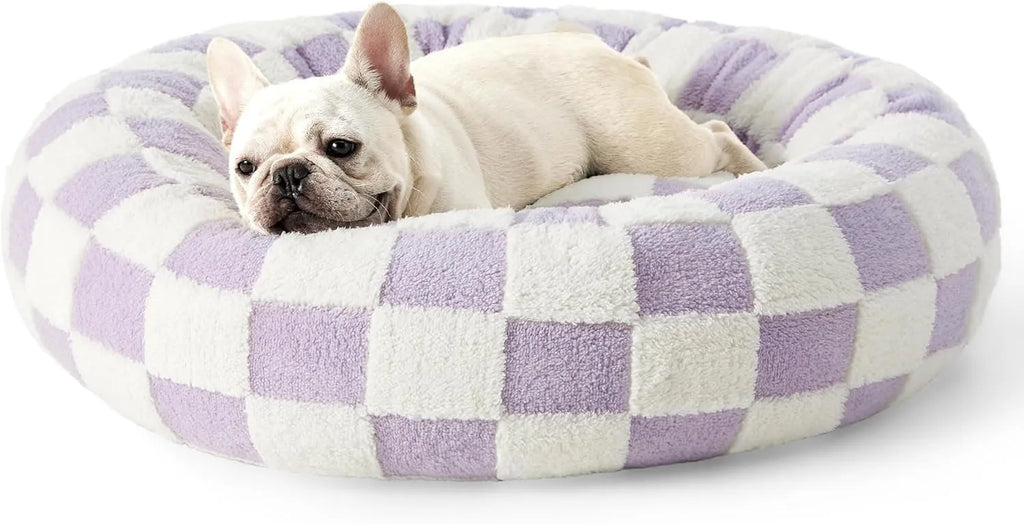 Round plaid dog bed with plastic base on a wooden floor