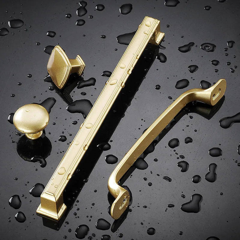Gold coloured aluminium T-shaped single hole cabinet door handle on white background