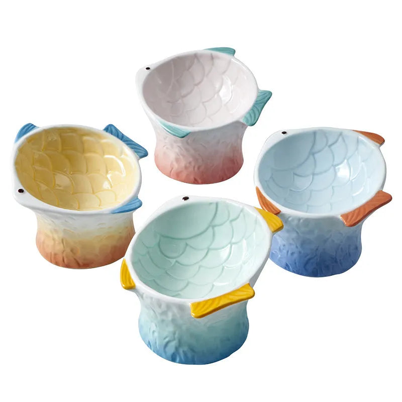 Blue ceramic cat food bowl in a fish shape with a tilted, elevated design and non-slip base.