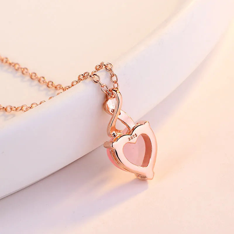 Rose gold women's necklace with a pink artificial crystal heart-shaped pendant on a cross chain