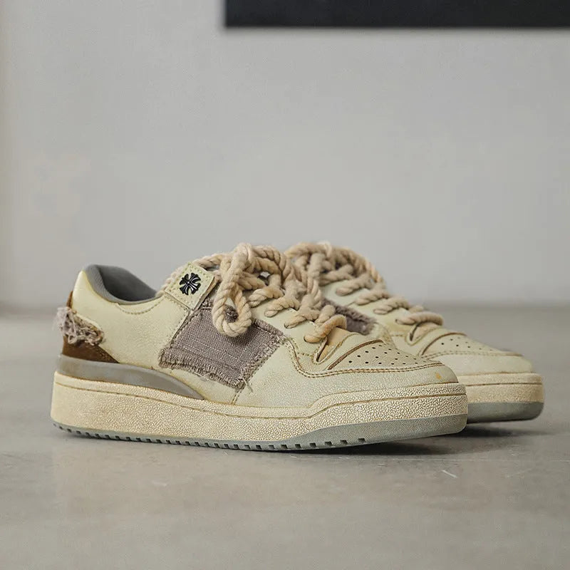 Beige low-top skateboard shoes with vintage patch detail and round toe on a rubber sole.