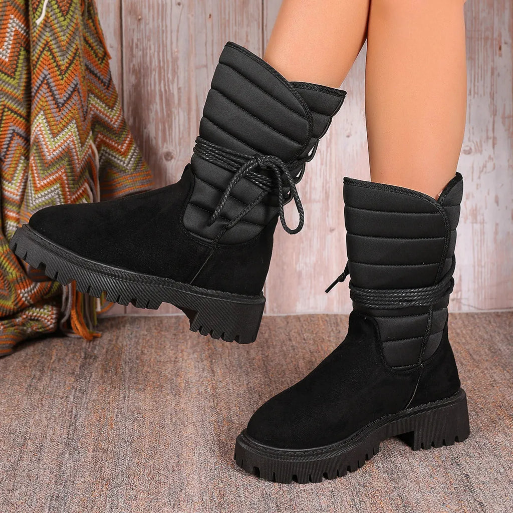 Women's black chunky heel snow boots with suede upper and lace-up design on a white background.