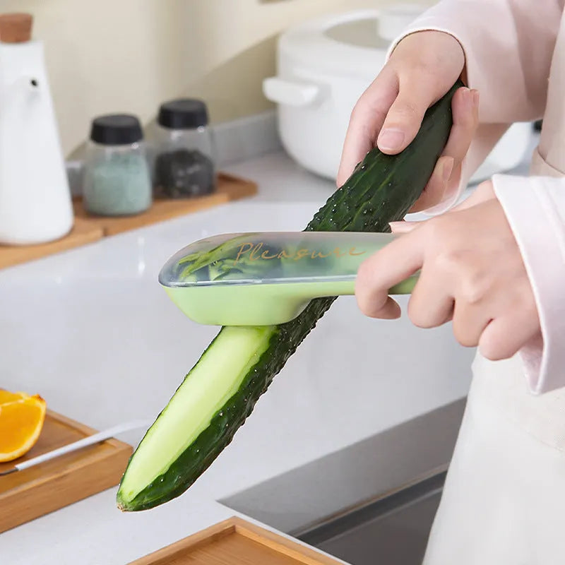 Dark green vegetable peeler with stainless steel blade inside its clear plastic storage tube on a kitchen counter.
