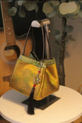 Gold PU leather small square handbag with tassels and sewing line detail on white background