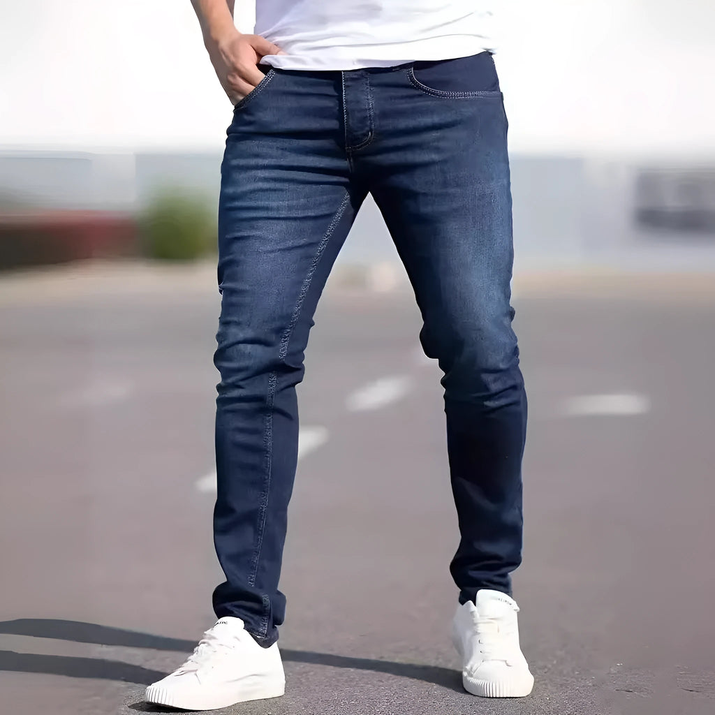 Dark blue men's skinny jeans with a mid-waist fit and zipper fly, laid flat.