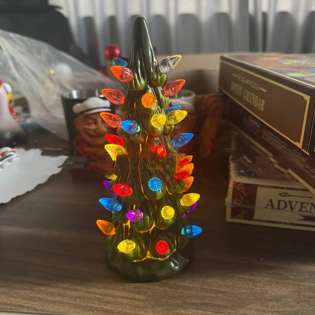 A resin Christmas tree-shaped lamp ornament with LED lights, shown in different sizes on a table.