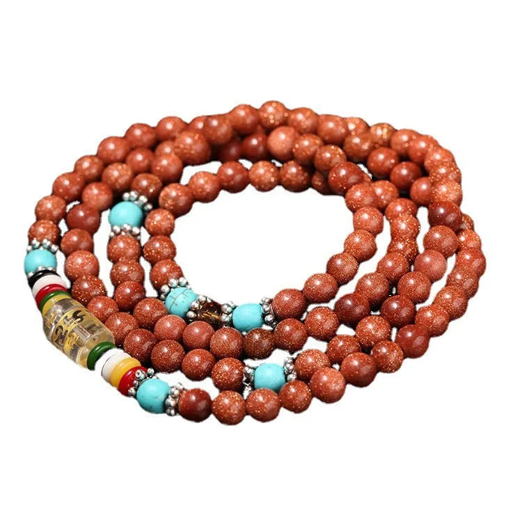 Golden star stone nugget bracelet with mantra beads and a retro fu charm on a wrist.