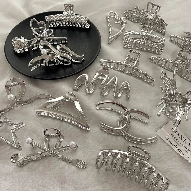 Assortment of silver metal hair barrettes and claw clips in various Korean-style designs on a white background.
