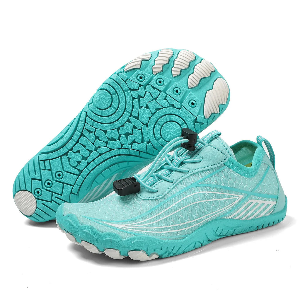 Children's elastic band water shoes in blue with a non-slip rubber sole, shown on a sandy beach.