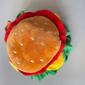 Cat wearing a foam burger headdress on a fabric cone collar for costume events.