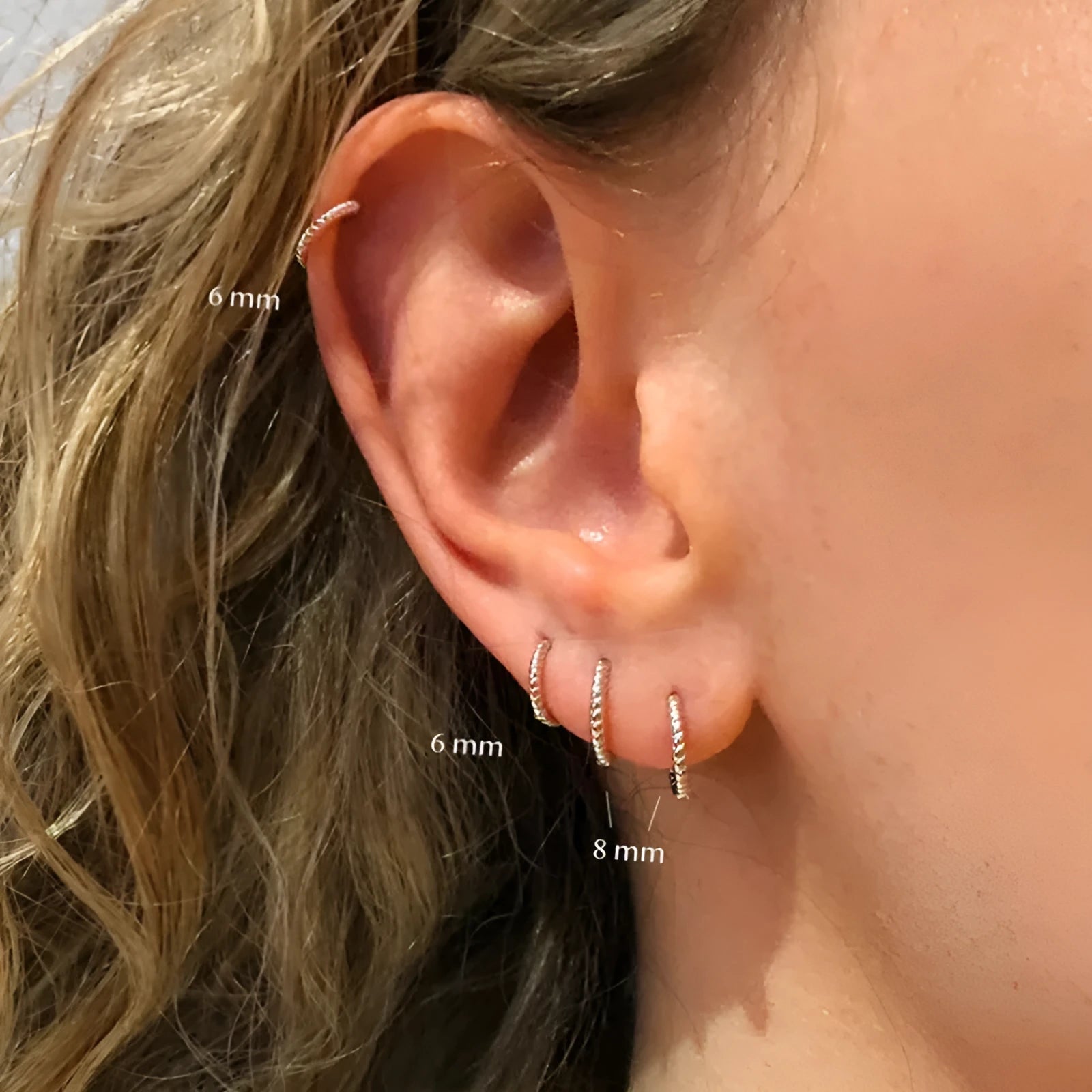 A pair of S925 sterling silver twisted string round hoop earrings on a gold background.