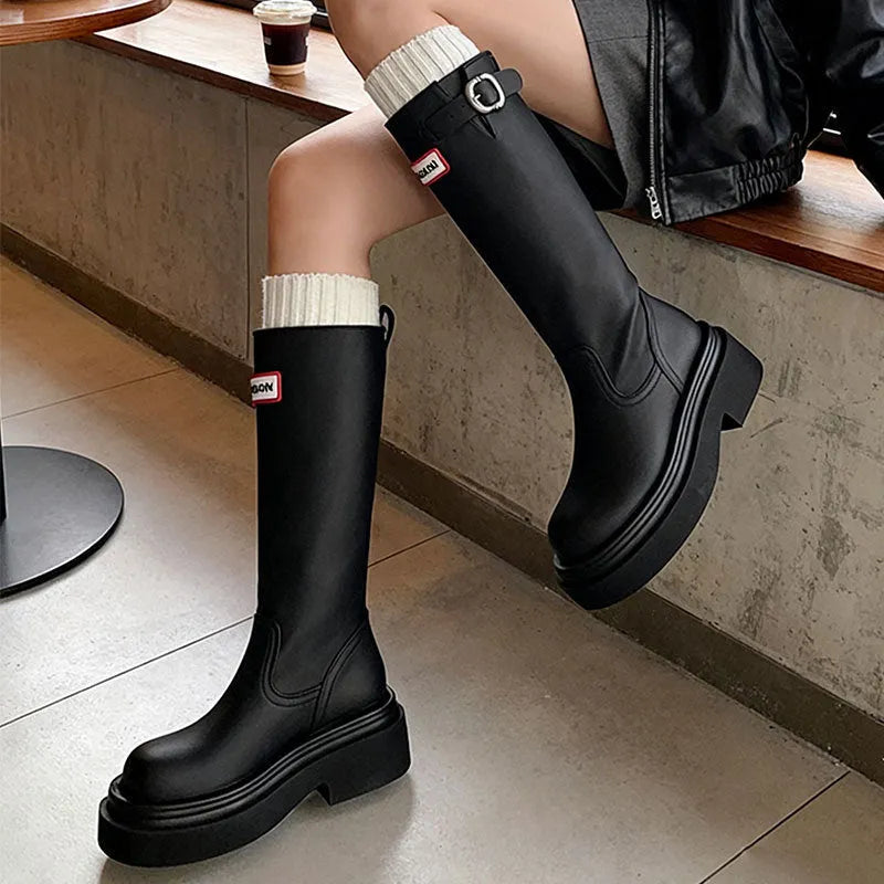 Black knight boots with thick platform sole and chunky heel, front view, showing round toe and high cylinder shaft.