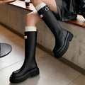 Black knight boots with thick platform sole and chunky heel, front view, showing round toe and high cylinder shaft.