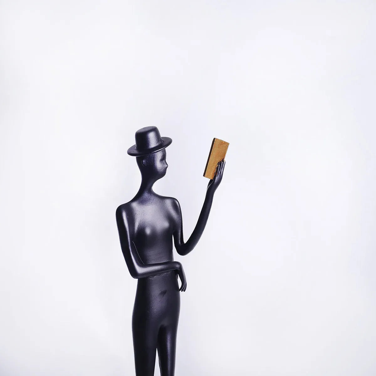 Black aluminium sculpture of reading woman for desktop decoration measuring 51cm tall
