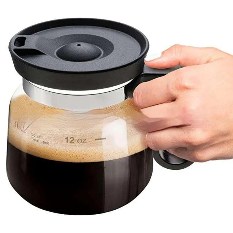Transparent borosilicate glass coffee maker with black silicone cover and handle on a stovetop.