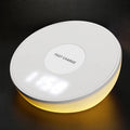 White wireless charging pad with LED digital clock display and control buttons on a desk.