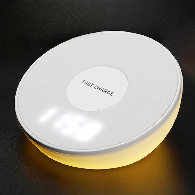 White wireless charging pad with LED digital clock display and control buttons on a desk.