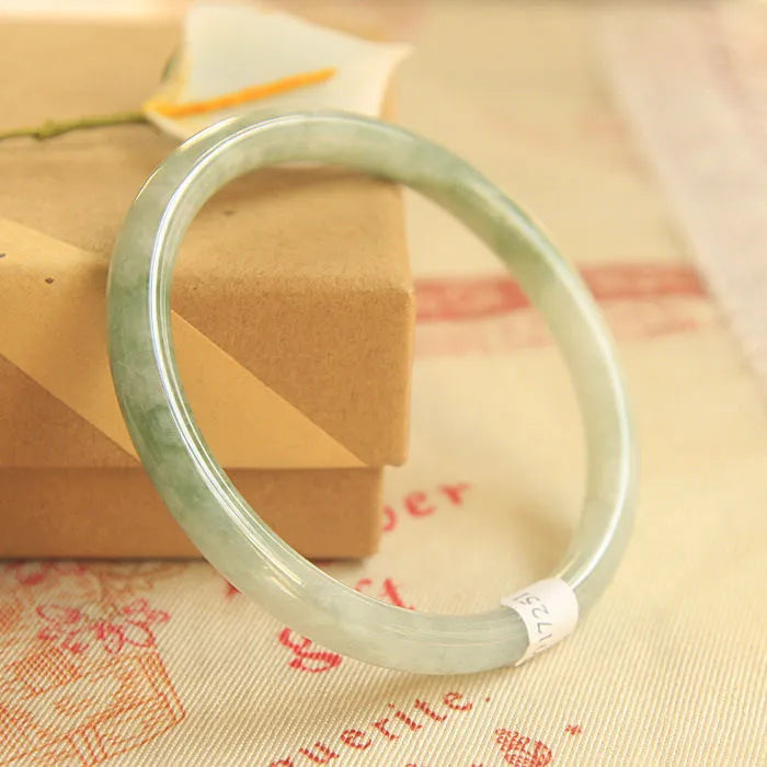Green jade waxy stone geometric bracelet with Chinese style design on a wrist.