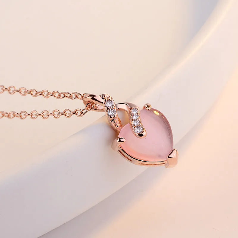 Rose gold women's necklace with a pink artificial crystal heart-shaped pendant on a cross chain