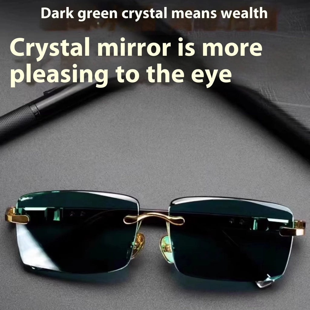 Dark green frameless crystal sunglasses with a matching case and cleaning cloth on a table.