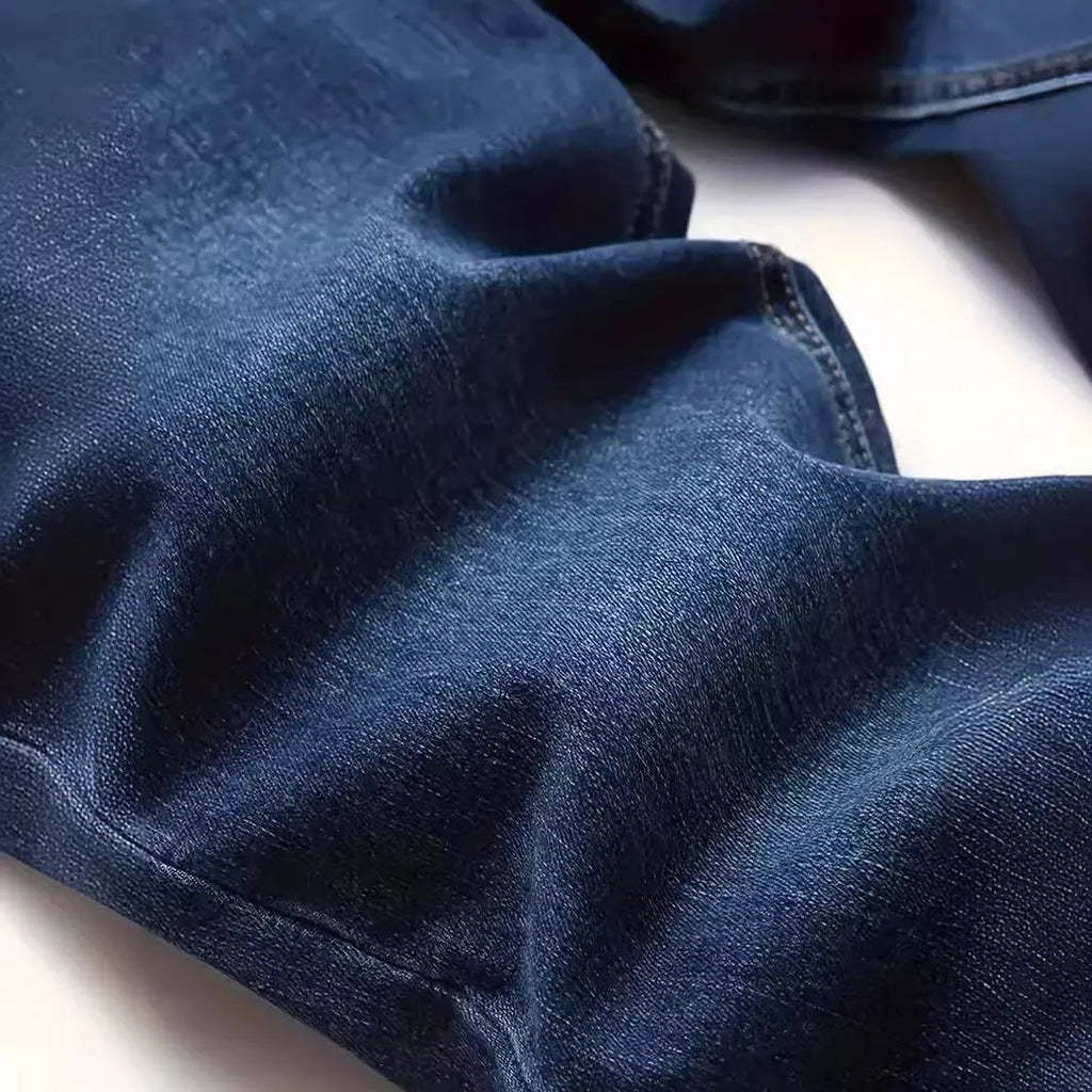 Dark blue men's skinny jeans with a mid-waist fit and zipper fly, laid flat.