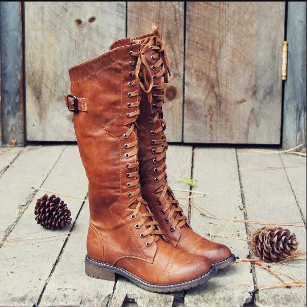 Women's black knight boots with cross-strap design across ankle in synthetic PU material