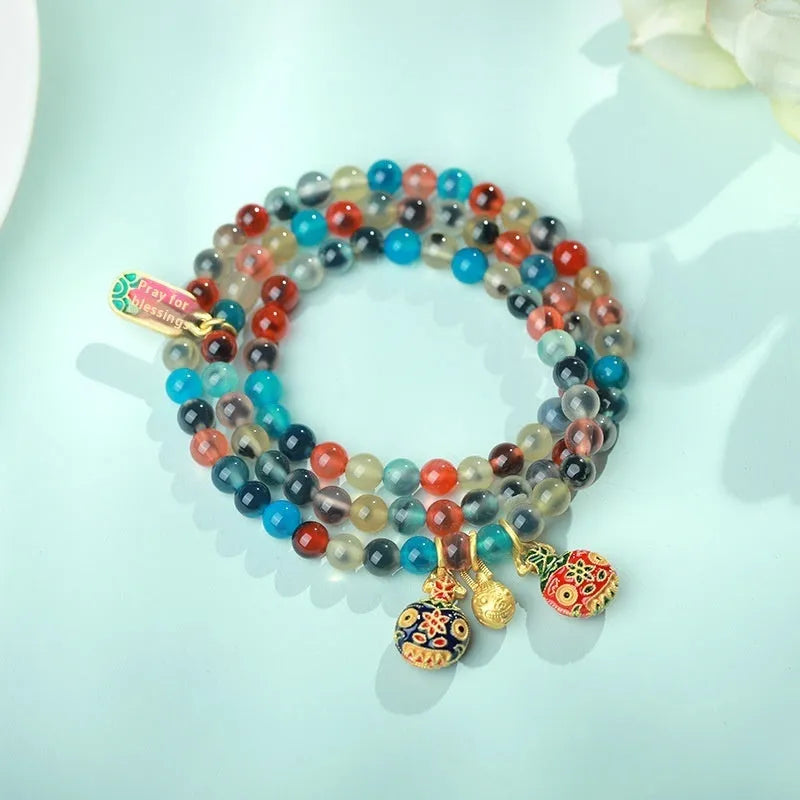 Natural agate and coloured glaze snake bracelet with copper coin charms on a white background.