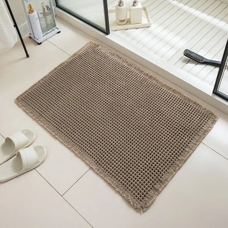 Checkered patterned non-slip absorbent bathroom floor mat in a neutral colour on tiles.