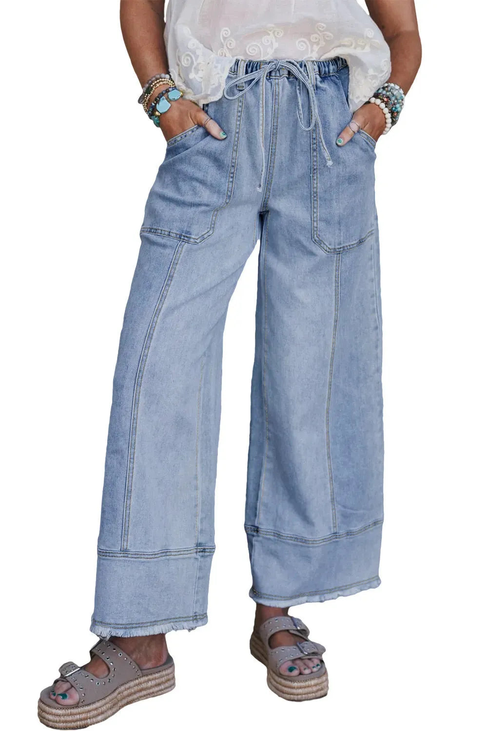 Beau blue wide leg denim trousers with a drawstring waist and raw hem detail laid flat.