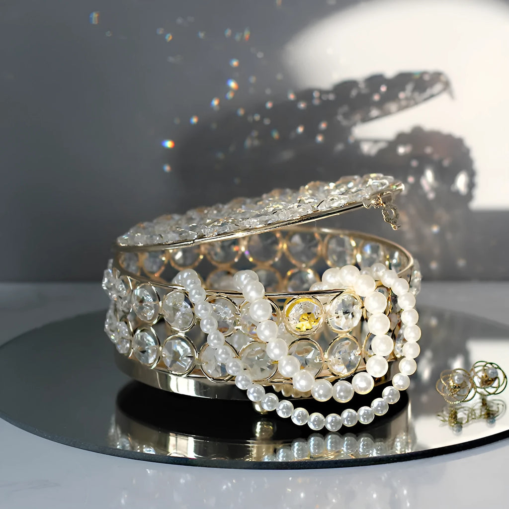 French gold iron jewellery box with a clear crystal glass lid on a wooden surface.