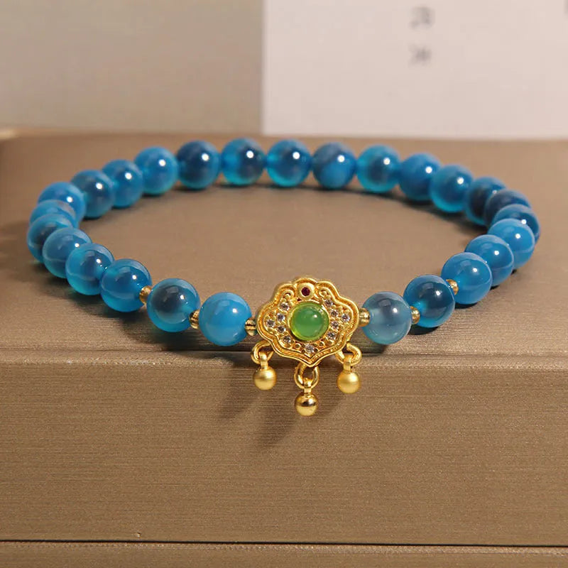 Close-up of a women's blue sugar heart agate safety lock pendant bracelet with crystal links and rhinestone detailing.