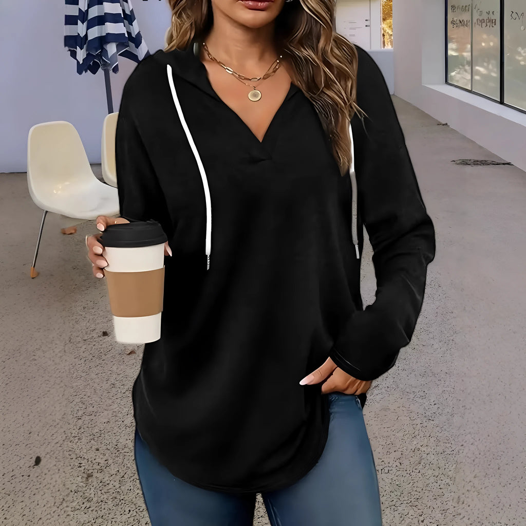 A woman wearing a red V-neck hooded sweatshirt with long sleeves, shown in a loose fit.