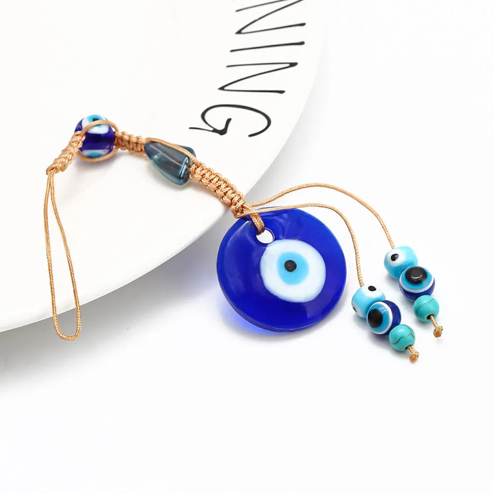Glass evil eye bead ornament with Turkish blue eye pattern and braided string for wall or car hanging