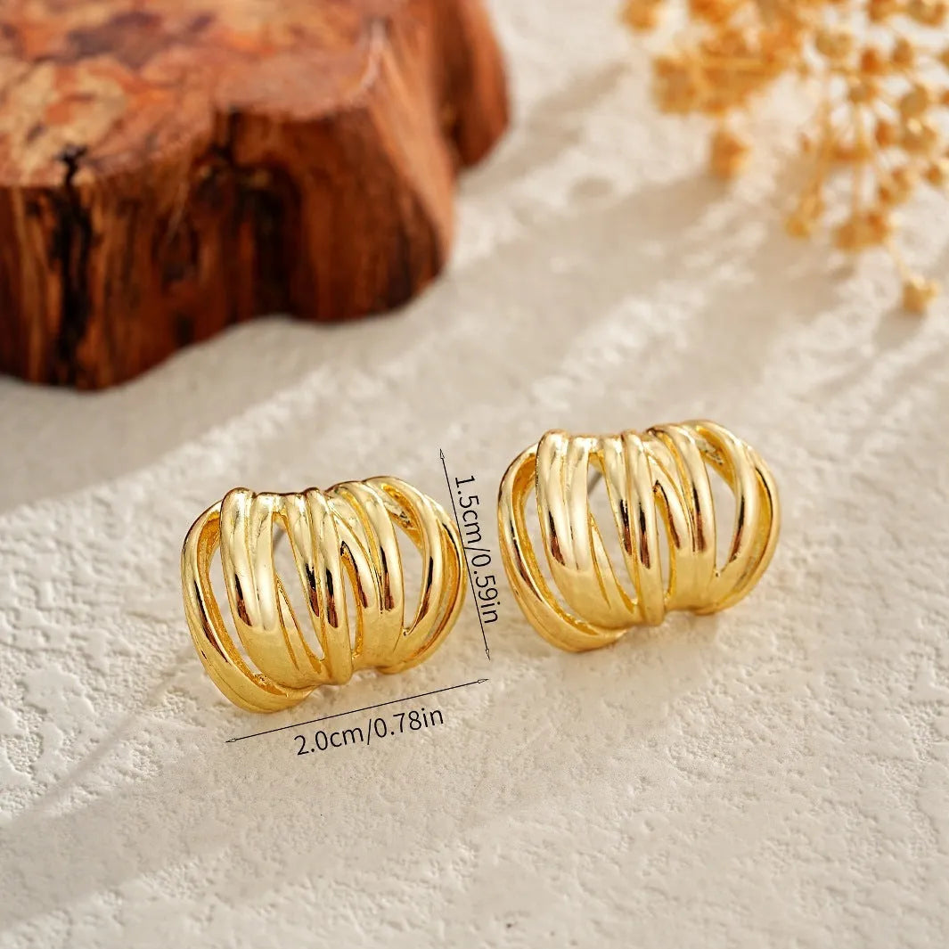 Gold metal ear loops with niche design and metal earrings on white background