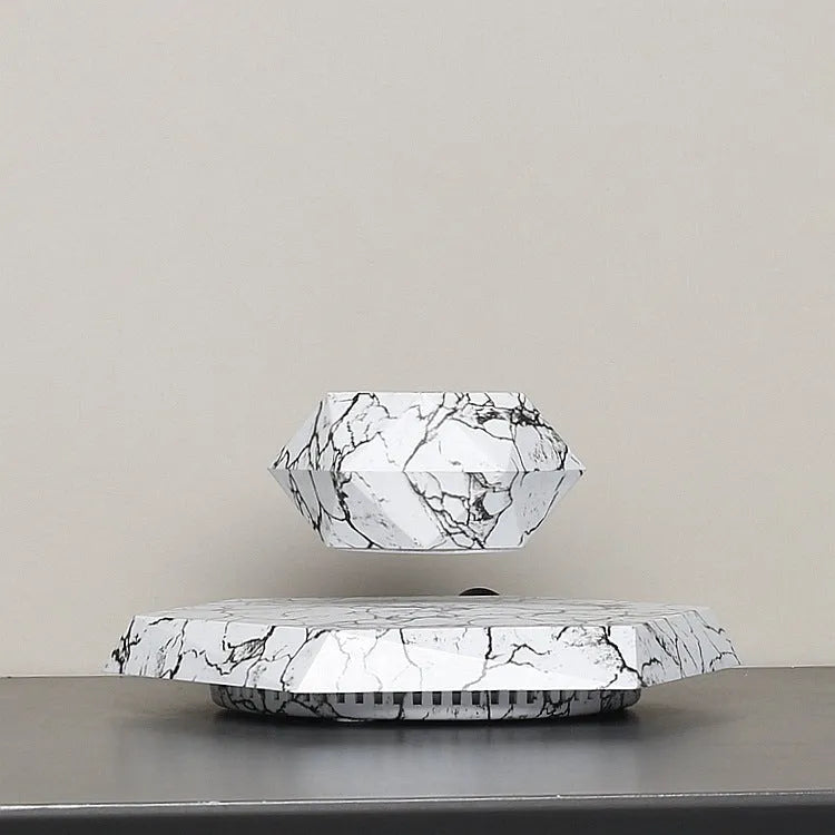 Small marble-colour levitating plant pot floating above its magnetic base on a desk.