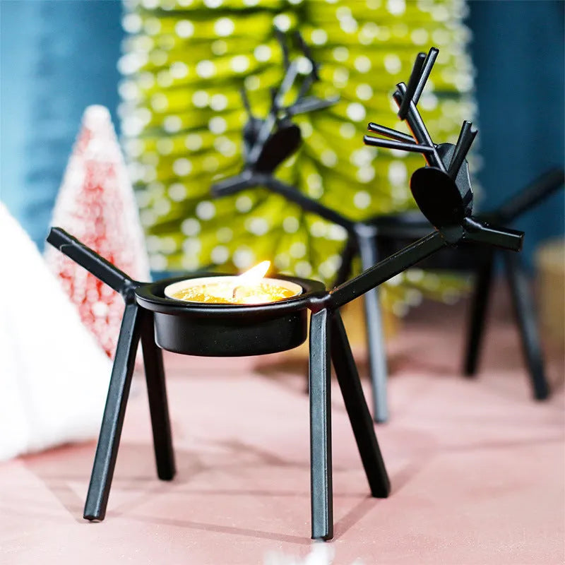 Black iron Christmas candlestick holder with decorative elk design on a festive table.