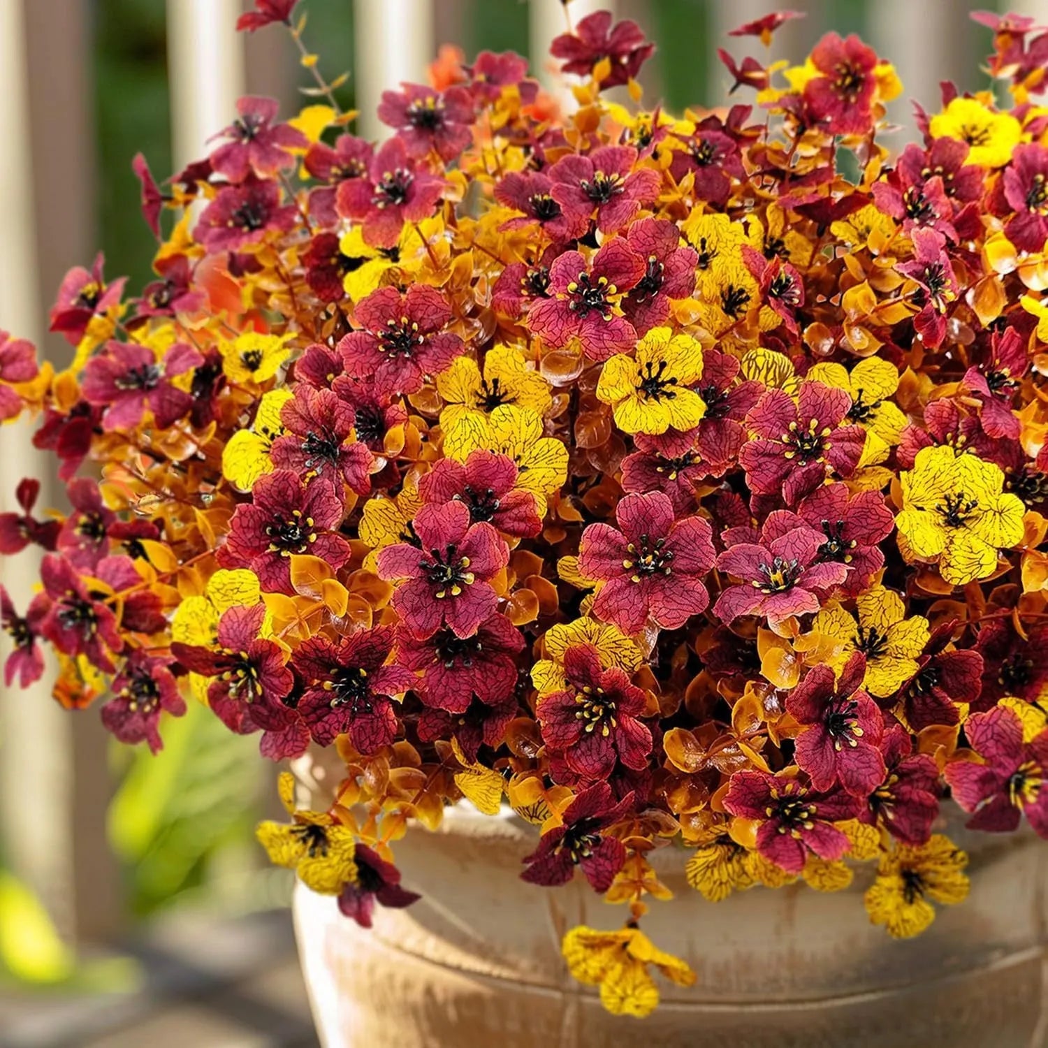 Plastic and silk artificial flower bouquet in autumn colours of red, yellow, orange and orange-yellow.