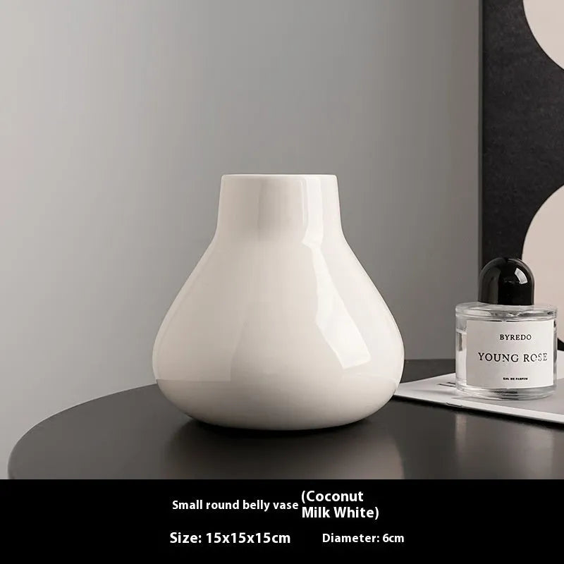 Black ceramic vase with round belly shape and two white flower ornaments arranged decoratively