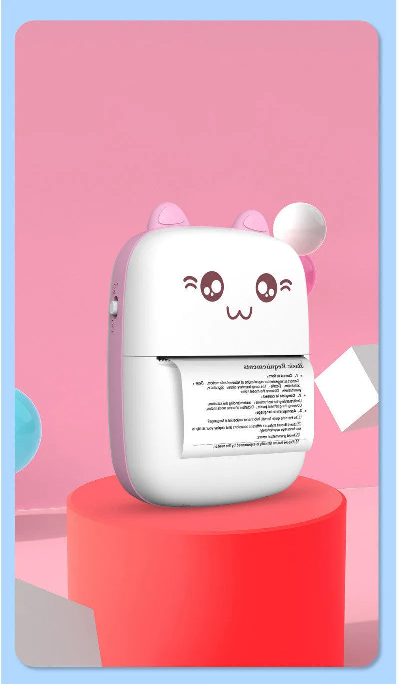 Pink mini Bluetooth thermal printer on a desk with a phone and printed note, measuring 11x8x3.5cm