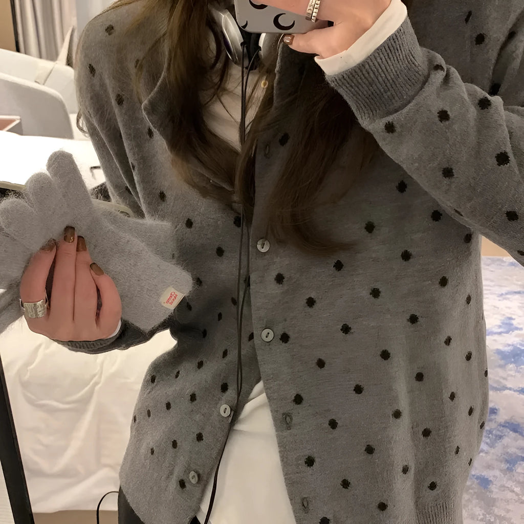 Women's grey dot pattern knitted cardigan with crocheted flower detail on a mannequin.