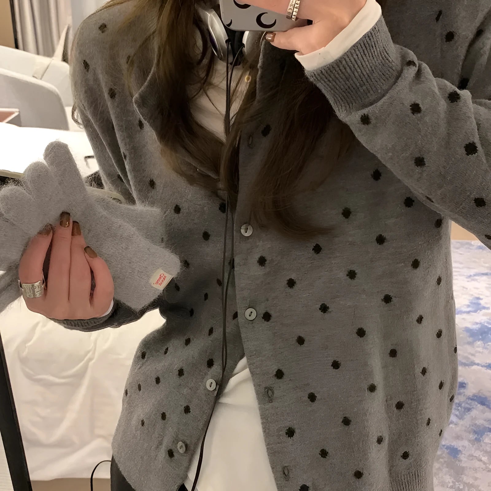 Women's grey dot pattern knitted cardigan with crocheted flower detail on a mannequin.