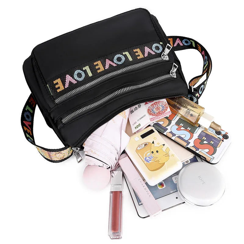 Oxford cloth crossbody shoulder bag in red or black with single strap, multi-pocket large capacity, and letter stitching details