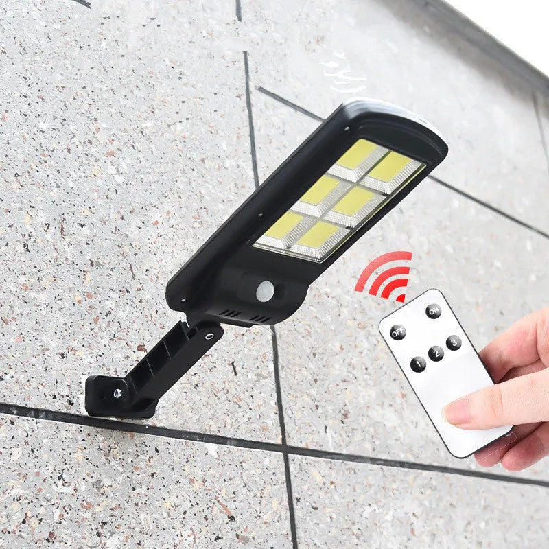 Black solar-powered outdoor security light with motion sensor mounted on a wall.