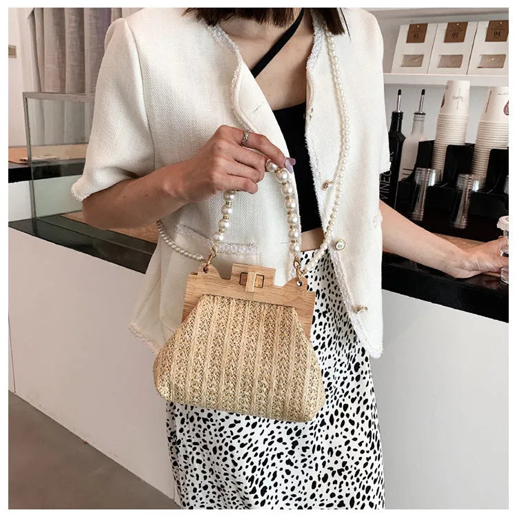 Women's horizontal square straw shoulder bag with pearl chain strap, shown in beige colour with visible sewing line detail.