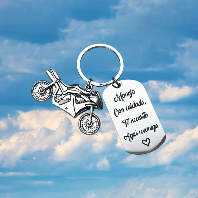 Stainless steel motorcycle key ring with velvet storage bag on a plain background.