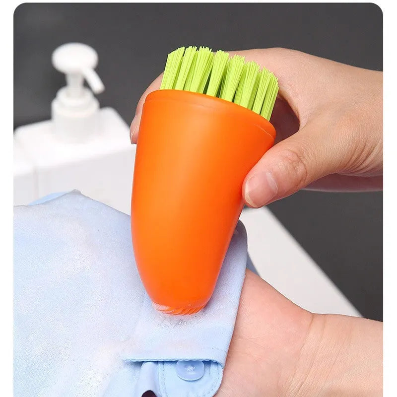 Orange and white carrot-shaped nylon kitchen cleaning brush with radish pattern on a wooden surface.