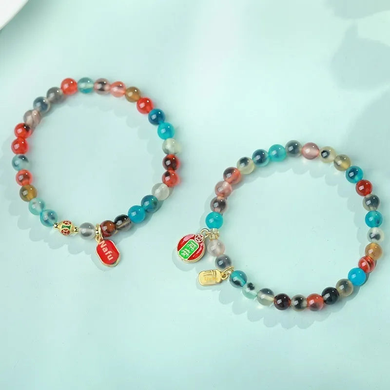 Natural agate and coloured glaze snake bracelet with copper coin charms on a white background.