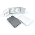 Black tri-fold Bluetooth keyboard shown folded and unfolded next to a smartphone