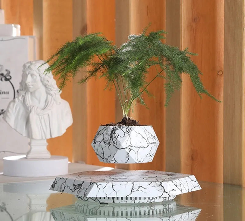 Small marble-colour levitating plant pot floating above its magnetic base on a desk.