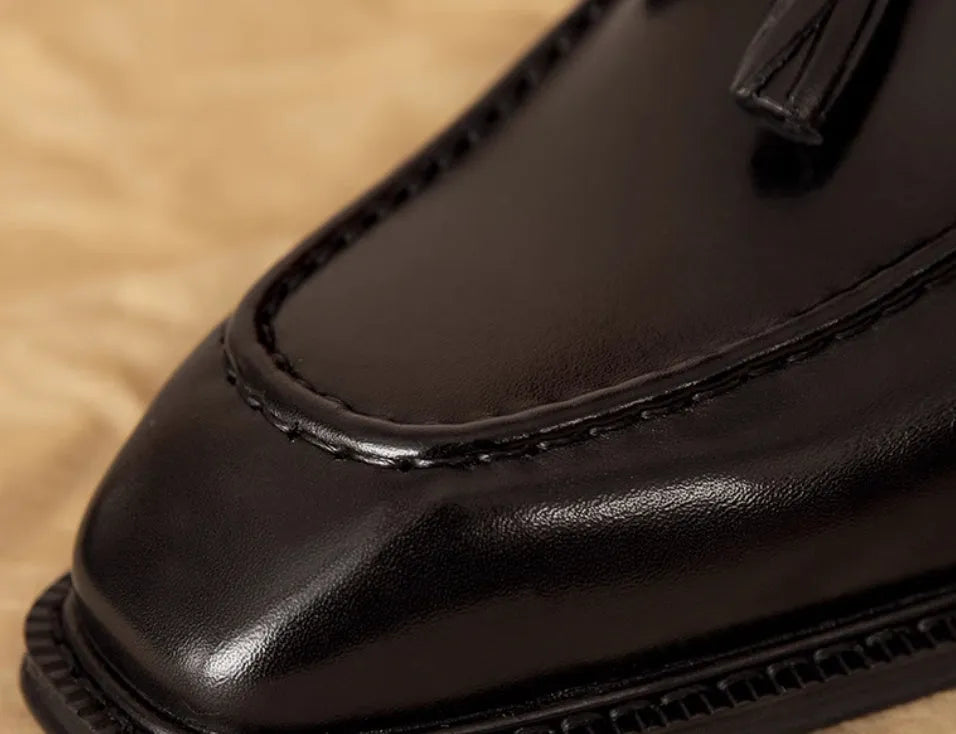 Men's black genuine leather slip-on loafers with a fringed design and rubber sole.